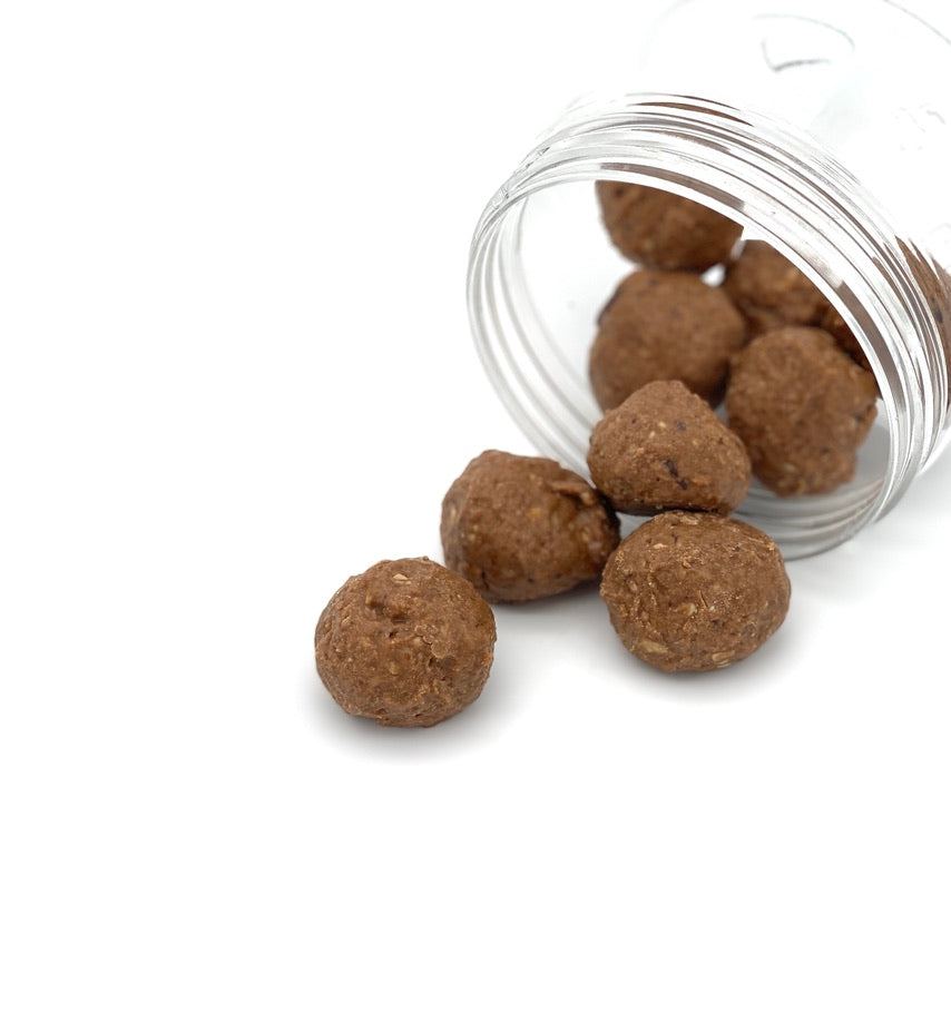 glass jar lying open on its side with date balls falling out of it.