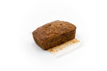 Load image into Gallery viewer, A single loaf of peanut butter banana bread placed on a piece of white parchment paper. The bread&#39;s rich, moist texture is evident, showcasing a well-baked crust with a golden-brown color. This delicious loaf is a perfect blend of peanut butter and banana flavors, appealing to anyone seeking a comforting and indulgent treat. Ideal for highlighting the bakery&#39;s specialty product.
