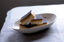 Load image into Gallery viewer, four millionaire shortbreads in a serving dish on a grey table cloth.
