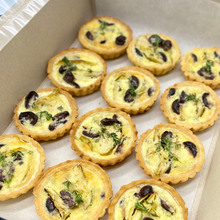 Load image into Gallery viewer, Twelve mini quiches in a box, garnished with fresh herbs and filled with artichokes and olives.
